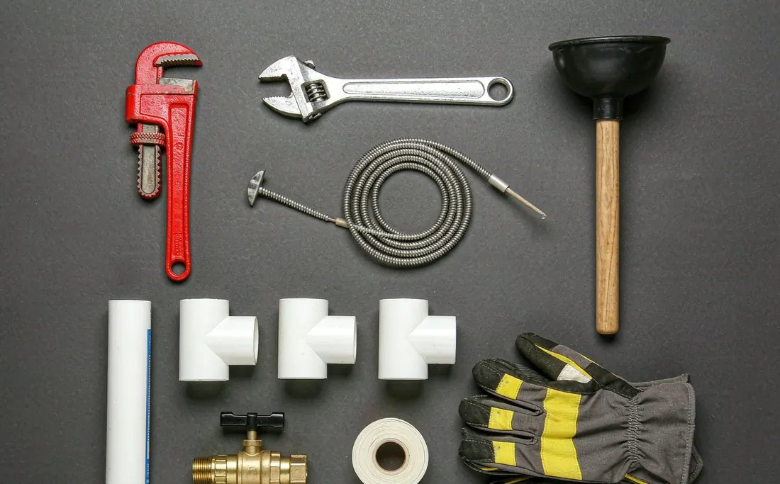 Plumbing tools and fittings laid out on a work surface