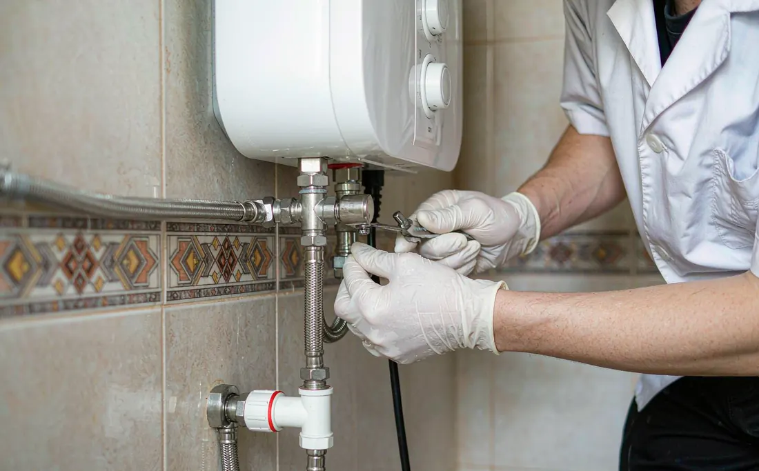 Wrench tightening the inlet hose on a wall-mounted water heater